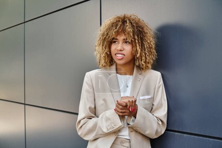 hopeful african american businesswoman in formal wear standing near office building, smile