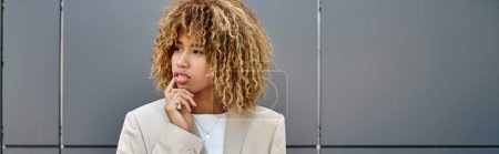Photo for Pensive african american businesswoman in formal wear looking away near office building, banner - Royalty Free Image