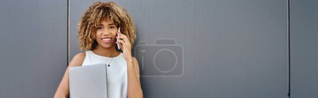 Photo for Banner of young professional, african american woman with laptop making a call against grey backdrop - Royalty Free Image