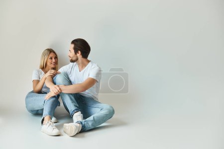 Foto de Un hombre y una mujer se sientan de cerca en el suelo, absortos en la conversación, bajo el brillo romántico del amor - Imagen libre de derechos
