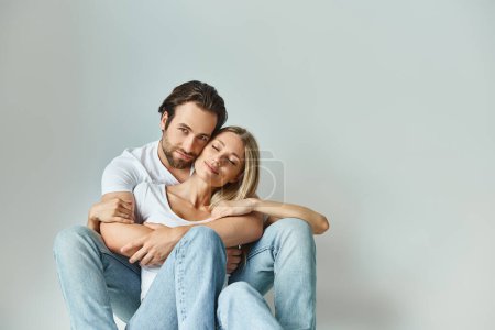 Un hombre y una mujer entrelazados en un abrazo apasionado, sentados uno encima del otro en una muestra de conexión íntima.