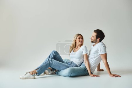 Téléchargez les photos : Un homme et une femme assis intimement sur le sol, respirant des vibrations romantiques et sereines - en image libre de droit