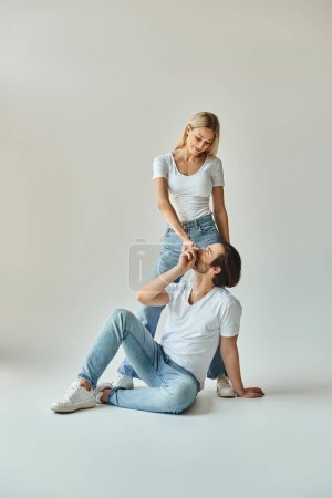 A man in casual attire sits peacefully on the ground next to a woman, sharing a moment of quiet togetherness.