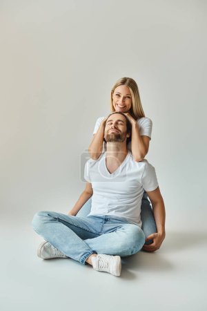 Ein Mann sitzt auf dem Boden, während die Frau auf seinem Rücken ruht und einen zarten und intimen Moment zwischen dem sexy Paar zeigt.