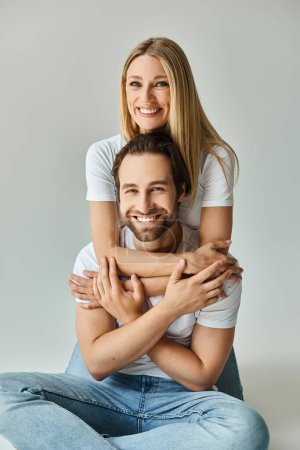Photo for A man, seated on the ground, carries a woman on his back in a romantic and intimate gesture of togetherness and connection. - Royalty Free Image