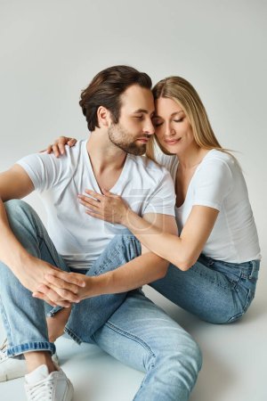 Ein Mann und eine Frau sitzen im Schneidersitz auf dem Boden, umarmen einander, strahlen Ruhe und Zuneigung aus.
