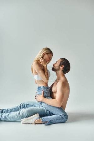Téléchargez les photos : Un homme et une femme, respirant une allure magnétique, partagent un moment intime assis sur le sol. - en image libre de droit
