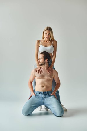 A man sits atop a woman on his back, showcasing a dynamic and intimate moment between the sexy couple.
