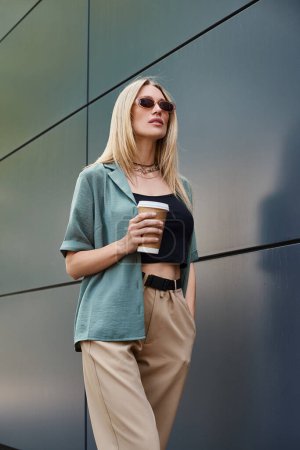 Una mujer sostiene alegremente una taza de café mientras está de pie junto a una pared, abrazando la calma de su rutina matutina.