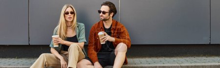 Téléchargez les photos : Un couple, exsudant sexiness et romance, s'assoit étroitement ensemble sur un trottoir dans un cadre urbain. - en image libre de droit