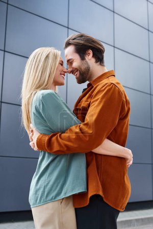 A man and a woman engage in a passionate embrace in front of a stylish building in a city setting.