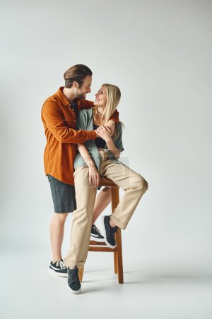 A man and a woman, exuding romance, sit closely together on a chair.