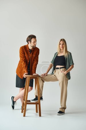 A man and a woman, exuding romance and sensuality, sit gracefully on a stool together.