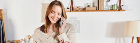 joven y alegre ama de casa hablando por teléfono móvil en apartamento moderno, pancarta horizontal