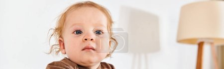 adorable little boy looking away in crib in comfortable nursery room at home, horizontal banner