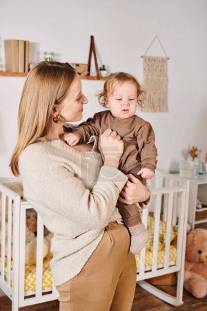 junge attraktive Frau mit entzückendem kleinen Sohn im gemütlichen Kinderzimmer, glückselige Mutterschaft