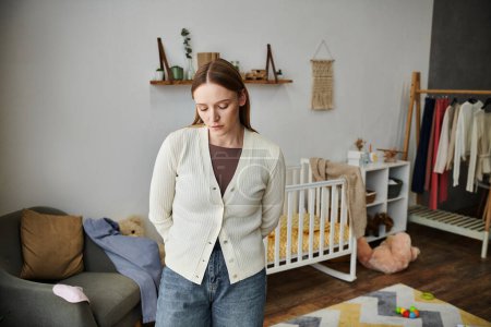 Photo for Heartbroken and depressed young woman standing in nursery room at home, grieving and frustration - Royalty Free Image