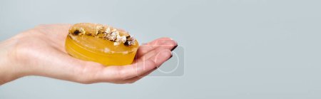 obiekt zdjęcie naturalnego mydła pomarańczowego z dekoracjami w dłoni nieznanej młodej kobiety, sztandar