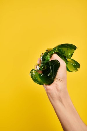 unknown young lady with nail polish squeezing green delicious jelly in her hand on yellow background