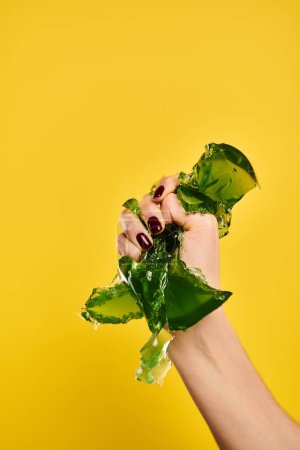 jeune femme inconnue avec vernis à ongles serrant vert gelée savoureuse dans sa main sur fond jaune