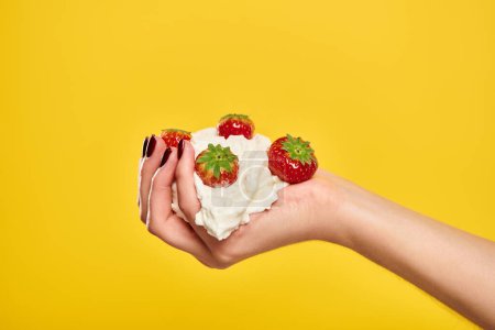 Objektfoto von köstlichen süßen roten Erdbeeren in Schlagsahne in den Händen einer unbekannten Frau