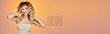 Téléchargez les photos : Femme heureuse avec les cheveux bouclés et la peau rayonnante posant sur le dégradé rose et jaune, bannière horizontale - en image libre de droit