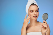 attractive woman with towel on head touching perfect skin on face on yellow backdrop, beauty magic mug #696259838