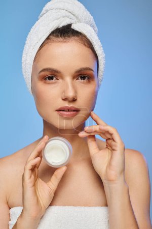 portrait of woman with towel on head holding jar of face cream on blue backdrop, wellness and beauty Mouse Pad 696260140