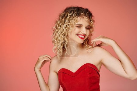 Téléchargez les photos : Femme élégante gaie avec lèvres rouges et haut posant avec les yeux fermés sur fond rose et jaune - en image libre de droit