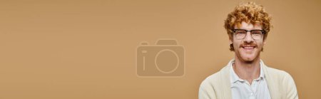 portrait of joyous redhead man in eyeglasses and stylish casual attire on beige backdrop, banner