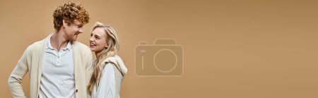 Photo for Happy blonde woman and redhead man in old money style clothes smiling at each other on beige, banner - Royalty Free Image