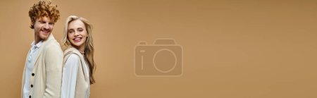 Téléchargez les photos : Heureux jeune couple en costume élégant de couleur claire posant dos à dos sur fond beige, bannière - en image libre de droit