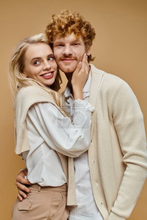 Photo for Fashionable couple in trendy old money style attire smiling and embracing on grey backdrop - Royalty Free Image