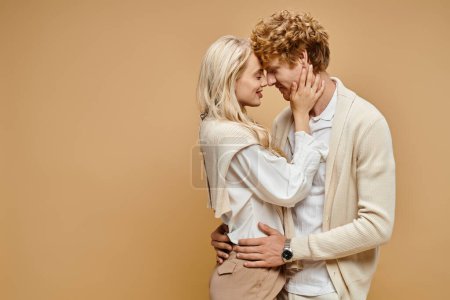 Foto de Vista lateral de la pareja de moda abrazando cara a cara con los ojos cerrados en color beige, viejo estilo de dinero - Imagen libre de derechos