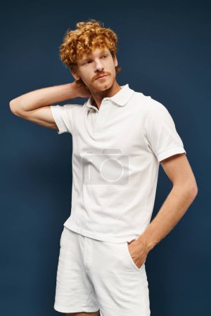 wealthy redhead man in white attire with hand in pocket looking away on blue, timeless fashion