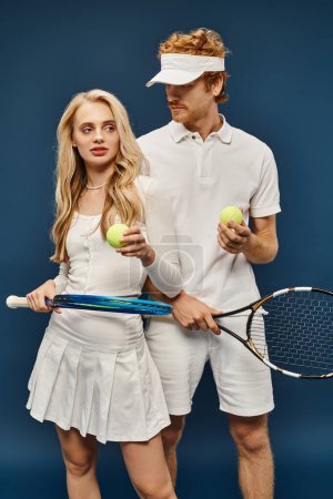 Photo for Fashionable young couple in white outfit with tennis racquets and balls on blue, old money style - Royalty Free Image