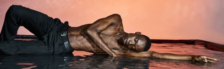 alluring african american man in wet pants lying on water surface with closed eyes, lights, banner