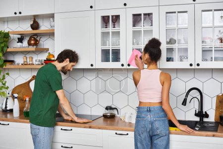 good looking diverse jolly couple in homewear during spring cleaning at home smiling happily
