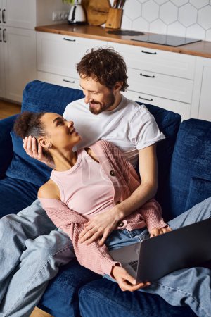 Téléchargez les photos : Beau beau gai divers couple regarder des films sur leur ordinateur portable et en regardant les uns les autres - en image libre de droit