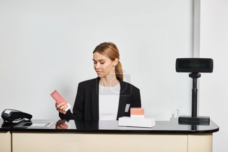 Téléchargez les photos : Bon assistant de magasin en blazer noir sophistiqué assis au comptoir et regardant les parfums - en image libre de droit