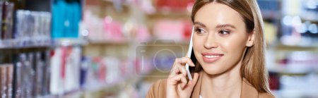Téléchargez les photos : Belle femme gaie en tenue décontractée d'affaires parlant par smartphone dans le magasin de cosmétiques, bannière - en image libre de droit