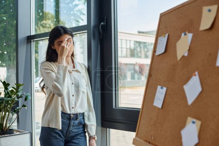 tired businesswoman stands by a window in a modern office,