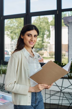 Photo for A businesswoman examines a clipboard by a sleek window in a modern office, embodying a pioneering franchise concept. - Royalty Free Image
