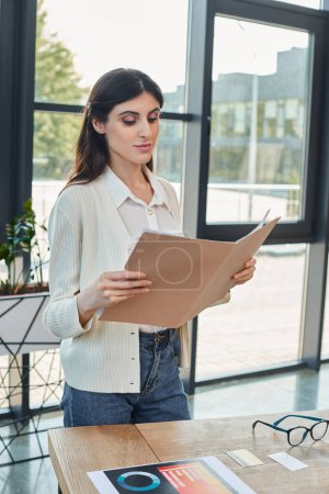 Eine Geschäftsfrau steht in einem modernen Büro, hält einen Zettel in der Hand, im Hintergrund ein Tisch, der auf ein Franchise-Konzept hindeutet..