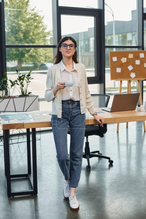 Una mujer de negocios está de pie con confianza junto a una mesa con una computadora portátil en un entorno de oficina moderno, encarnando el concepto de franquicia.