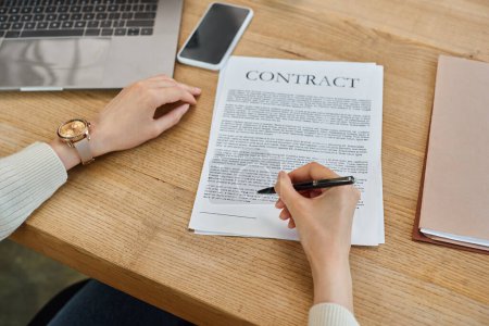 Une femme d'affaires dans un bureau moderne assis à une table, axée sur la signature d'un contrat lié à un concept de franchise.
