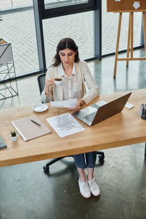 A businesswoman sits with a laptop in a modern office, working on franchising concepts and strategies.