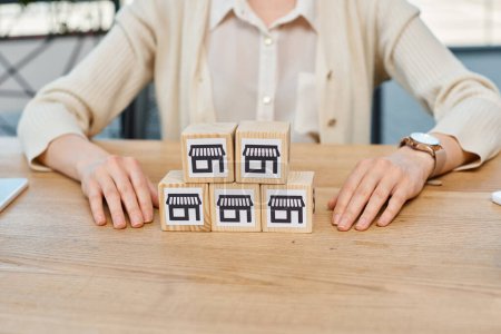 Photo for A businesswoman sits at a table, contemplating a set of blocks in front of her, symbolizing the concept of building business dreams. - Royalty Free Image