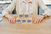 A businesswoman sits at a table, contemplating a set of blocks in front of her, symbolizing the concept of building business dreams. puzzle #697226142