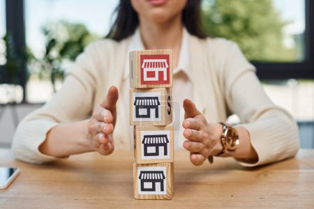 Photo for A businesswoman sits at a table, engaging in a franchise concept, with a stack of blocks representing growth and innovation. - Royalty Free Image